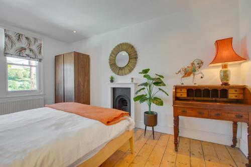 ein Schlafzimmer mit einem Bett, einem Schreibtisch und einem Spiegel in der Unterkunft North End House in Fowey
