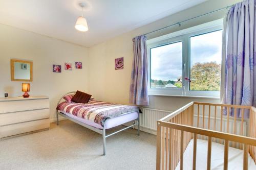 a small bedroom with a crib and a window at Castle View in Saundersfoot
