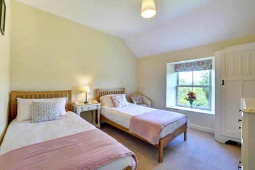 a bedroom with two beds and a window at St Teresas Cottage in Saint Mawgan