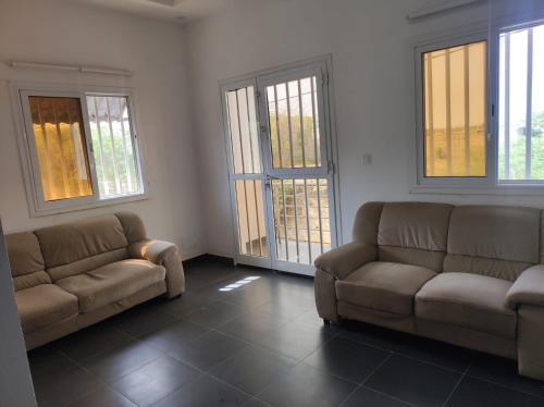 a living room with two couches and two windows at casa mara dakar in Bargny