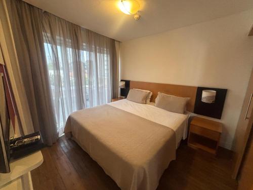 a bedroom with a white bed and a large window at Flat Lindo ao lado Park Ibirapuera Av Paulista com garagem 103 in Sao Paulo