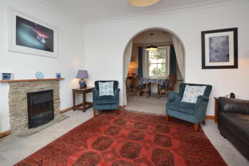 a living room with a fireplace and a couch and chairs at St Gwithians in Porthleven