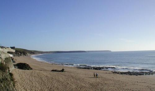 a beach with people walking on the sand and the water at St Gwithians in Porthleven