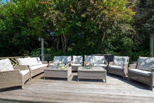 a group of wicker chairs and tables on a wooden deck at Brambles in Croyde