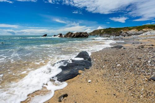 a rock in the water on a beach at Valpre in Manaccan