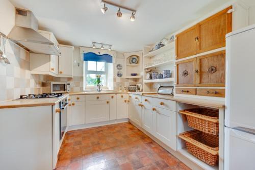 a kitchen with white cabinets and a tile floor at Ynys Pandy in Llanfihangel-y-pennant
