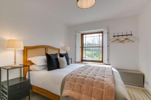 a bedroom with a large bed and a window at Higher Treliver Farmhouse in Saint Wenn