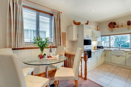 a kitchen with a glass table and white cabinets at Windrush in Croyde