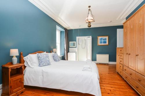 a bedroom with a white bed and blue walls at Boslandew House in Paul
