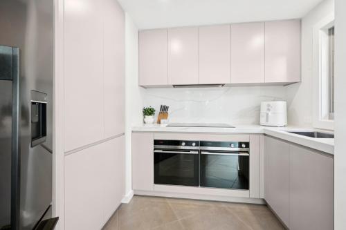 a white kitchen with white cabinets and a dishwasher at Gerald's Break Away - Style and luxury with Pool in Kororo Basin
