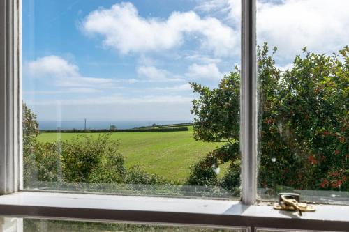 an open window with a view of a green field at Boslandew House in Paul