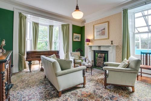 a living room with green walls and a piano at Boslandew House in Paul