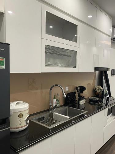 a kitchen with white cabinets and a sink at Romaji House in An Khê
