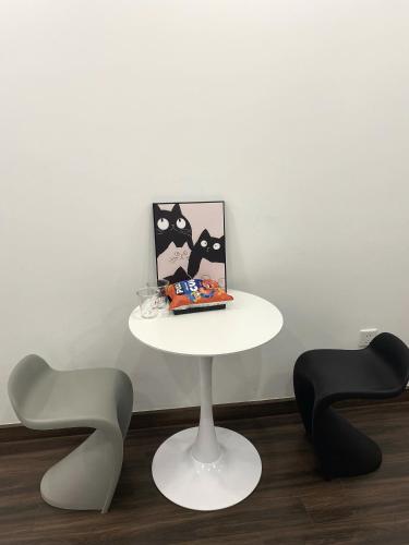 a white table with a picture and two chairs at Romaji House in An Khê