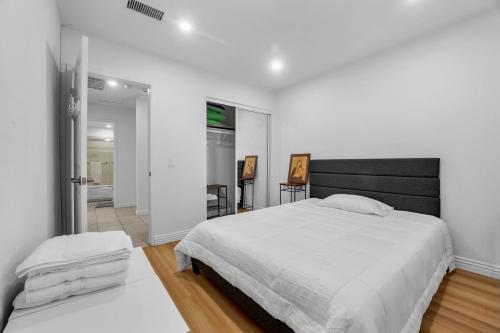 a white bedroom with a large bed and a hallway at Modern Cali Comfort- Spacious 3BR Home Near Disneyland & Beaches in Midway City
