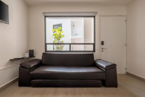a leather couch in a living room with a window at Senda Santa Fe Gym WiFi Parking in Cedro