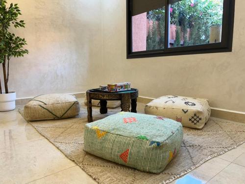 a living room with three ottomans and a table at Villa Palmeraie Luxe, 7 min de Geliz & Piscine Privée in Marrakech