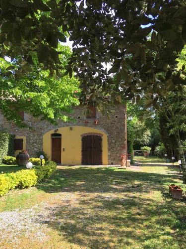 a stone building with two doors in a yard at Podere Casanova in Montespertoli