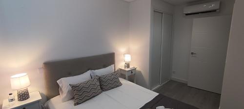 une chambre avec un lit avec des oreillers et deux lampes dans l'établissement Skynest 59 Faro Airport Guest House, à l'aéroport de Faro