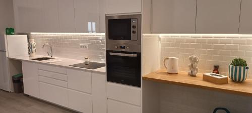 une cuisine blanche avec un évier et un micro-ondes dans l'établissement Skynest 59 Faro Airport Guest House, à l'aéroport de Faro