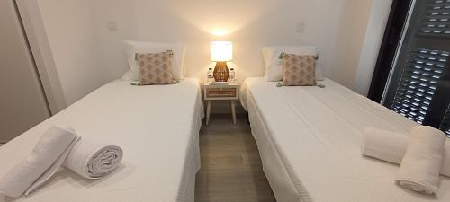 deux lits dans une chambre avec une lampe sur une table dans l'établissement Skynest 59 Faro Airport Guest House, à l'aéroport de Faro