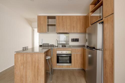 a kitchen with wooden cabinets and a stainless steel refrigerator at Senda Santa Fe Gym WiFi Parking in Cedro