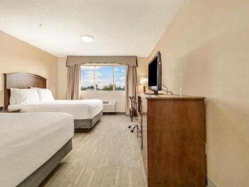 a hotel room with two beds and a television at Holiday Inn Lethbridge by IHG in Lethbridge
