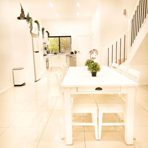 a white dining room with a white table and chairs at The Frederick Guest House in Sydney