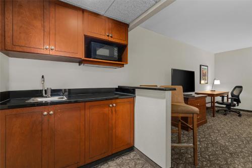 a kitchen with wooden cabinets and a desk with a microwave at Drury Plaza Hotel St Louis Creve Coeur in Creve Coeur