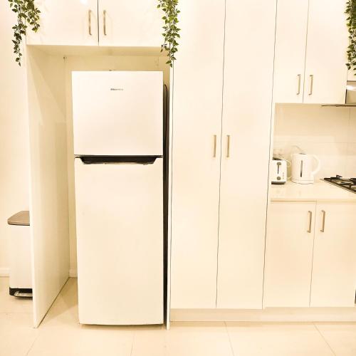 a refrigerator in a kitchen with white cabinets at The Frederick Guest House in Sydney