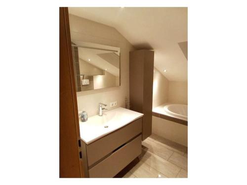 un bagno con un lavandino, uno specchio e una vasca di Holiday apartment with 2 bedrooms a Prackenbach