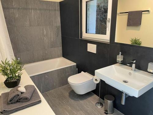 Un baño con lavabo, inodoro y bañera. en 1-bedroom holiday home, en Arcegno