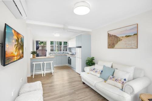 a living room with a white couch and a kitchen at Belle Escapes Relax Rose in Palm Cove