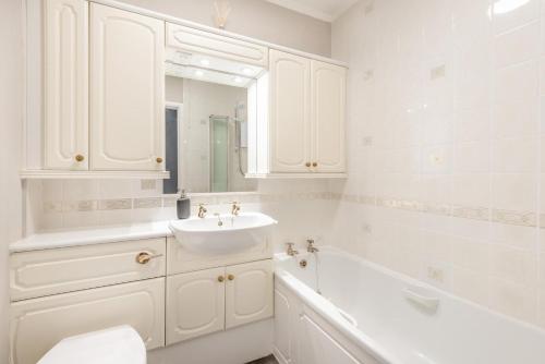 une salle de bain blanche avec un lavabo et une baignoire dans l'établissement Mews Cottage, à Grasmere