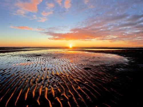 a sunset on a beach with ripples in the sand at Schroeder's House Kampen House 2 in Kampen