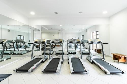 a gym with a row of treadmills and mirrors at Hotel La Fontaine in Esmoriz
