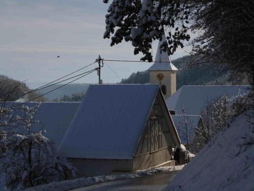 a church with a snow covered roof and a steeple at Holiday home in Wutach with swimming pool in Lembach