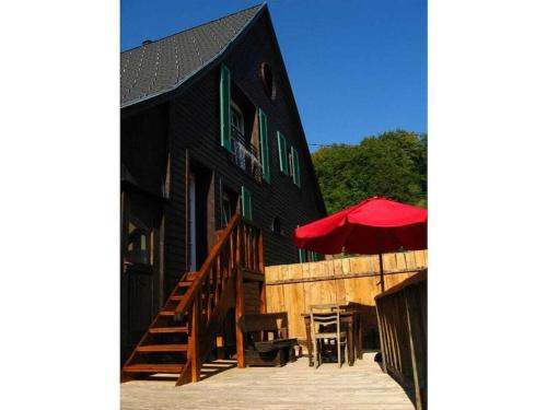 a black building with a red umbrella and some tables at Holiday home in Wutach with swimming pool in Lembach