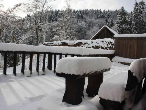 a bench covered in snow next to a fence at Holiday home in Wutach with swimming pool in Lembach