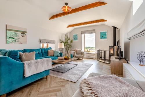 a living room with a blue couch and a table at Traeth Barn in Mawgan Porth