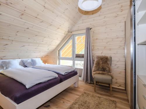 Un dormitorio con una cama y una silla y una ventana. en Bergwaldlodge Blickfang, en Schierke