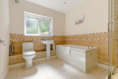 Un baño con bañera, inodoro y lavabo. en Milton Lodge, en Little Petherick