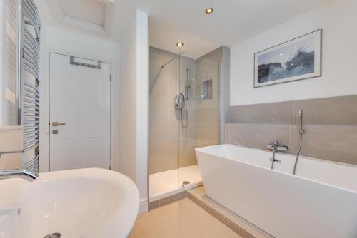 a white bathroom with a tub and a sink at Kittiwake Padstow in Padstow