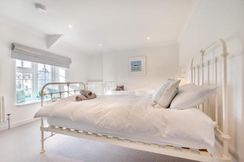a white bedroom with a white bed with white sheets at Elmwood Cottage in St Merryn