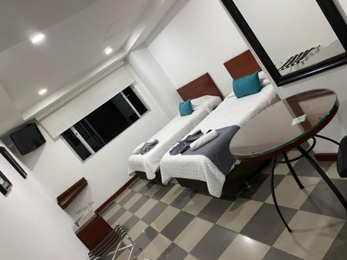 1 dormitorio con 2 camas y mesa de cristal en MV Hotel Kafir, en Bogotá
