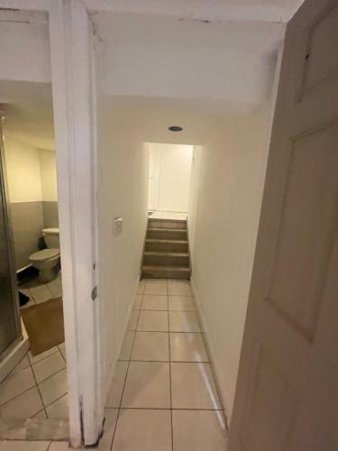 a hallway with stairs leading to a room with white walls at Hollow high hill Ranch retreat in Dix Hills