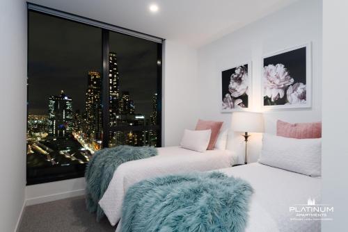 a bedroom with two beds and a large window at Platinum Luxury Stays at Aston in Melbourne