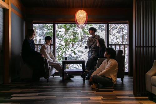 eine Gruppe von Menschen, die in einem Raum sitzen in der Unterkunft NOMADO HOTEL daisen in Hoki
