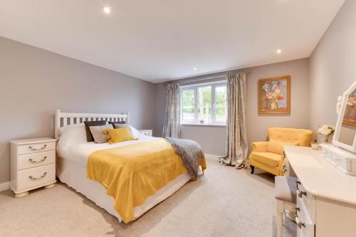 a bedroom with a bed and a yellow chair at Valley View in Mevagissey