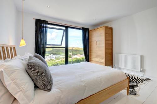 a bedroom with a large bed with a large window at Pen Y Mor in Mawgan Porth